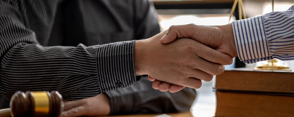 An Albuquerque Asylum Lawyer shaking hands with a client over legal documents and a pen.