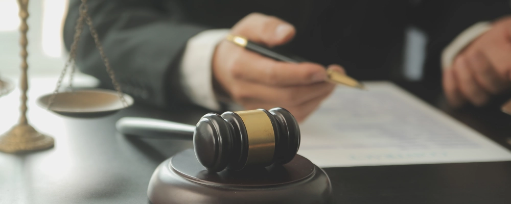 A gravel and hammer in the foreground with an Albuquerque Non-Immigrant Visa lawyer reviewing a document in the background.