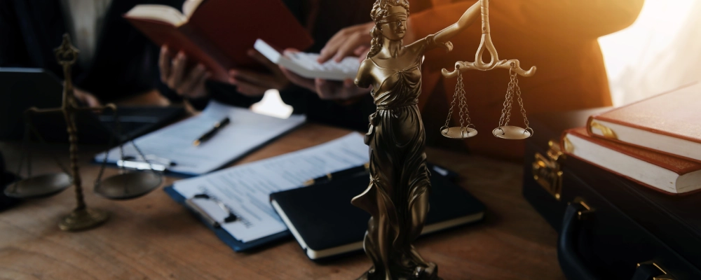 Albuquerque Student Visa Lawyers reviewing legal documents around a table with a statue of Lady Justice displayed in the foreground.