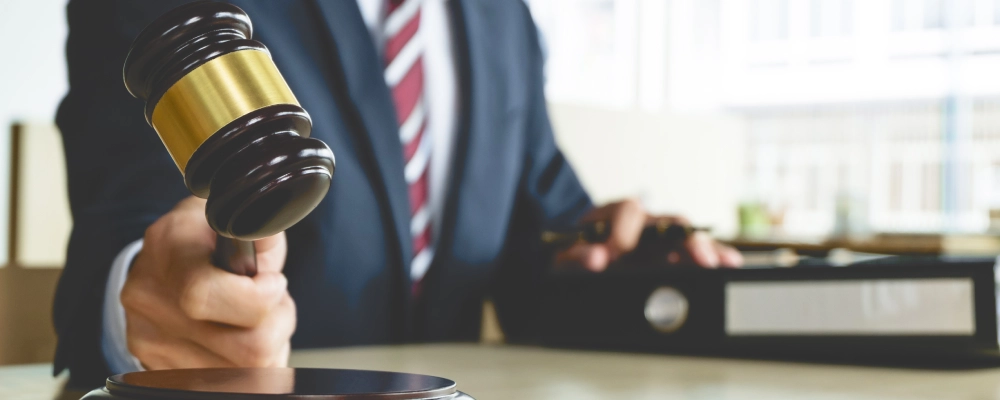 A DACA immigration lawyer holding a gavel and resting a hand over a binder of documents.
