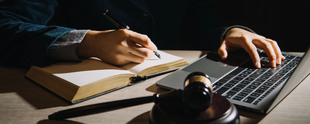 A Dallas Green Card Lawyer writing notes while working on his laptop.