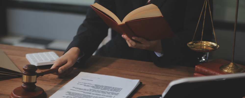 A Garland Immigration lawyer stands while reading a law book and holding a hammer in one hand