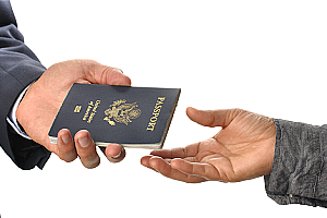 A closeup of an immigration lawyer's arm handing a passport to his client.